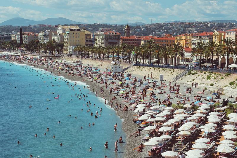 Plage de Nice avec ses rangées de parasols blancs et la mer turquoise